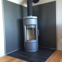 medium grey non-combustible aluminum panels behind soapstone woodstove