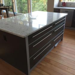 mobles de cuina en gris amb accents en plata; encimera de pedra natural, cuina alumini